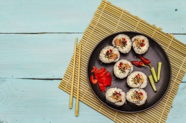 Kore usulü Gimbap (kimbob). Buğulanmış beyaz pirinç (bap) ve diğer malzemeler. Moda turkuaz ahşap tahta arka plan