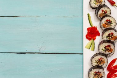 Kore usulü Gimbap (kimbob). Buğulanmış beyaz pirinç (bap) ve diğer malzemeler. Moda turkuaz ahşap tahta arka plan