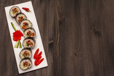 Kore usulü Gimbap (kimbob). Buğulanmış beyaz pirinç (bap) ve diğer malzemeler. Moda siyah tahta kaplama arka planı