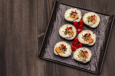 Kore usulü Gimbap (kimbob). Buğulanmış beyaz pirinç (bap) ve diğer malzemeler. Moda siyah tahta kaplama arka planı