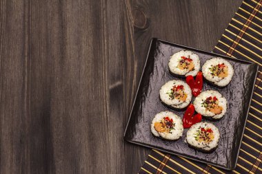 Kore usulü Gimbap (kimbob). Buğulanmış beyaz pirinç (bap) ve diğer malzemeler. Moda siyah tahta kaplama arka planı