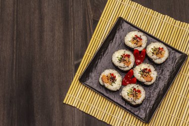 Kore usulü Gimbap (kimbob). Buğulanmış beyaz pirinç (bap) ve diğer malzemeler. Moda siyah tahta kaplama arka planı