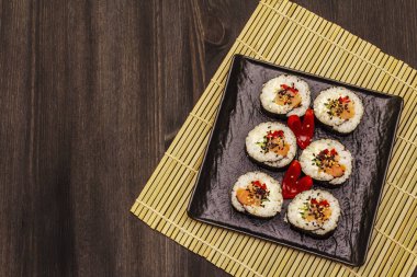 Kore usulü Gimbap (kimbob). Buğulanmış beyaz pirinç (bap) ve diğer malzemeler. Moda siyah tahta kaplama arka planı
