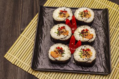 Kore usulü Gimbap (kimbob). Buğulanmış beyaz pirinç (bap) ve diğer malzemeler. Moda siyah tahta kaplama arka planı
