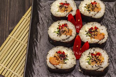 Kore usulü Gimbap (kimbob). Buğulanmış beyaz pirinç (bap) ve diğer malzemeler. Moda siyah tahta kaplama arka planı