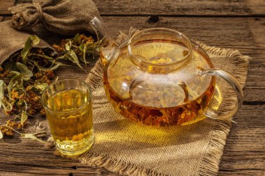 Linden çayı. Kuru kokulu çiçekler. Güneşli sabah kahvaltısı. Bağışıklık sistemini güçlendirmek için sıcak içecek, alternatif tıp. Klasik ahşap masa.