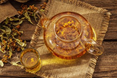 Linden çayı. Kuru kokulu çiçekler. Güneşli sabah kahvaltısı. Bağışıklık sistemini güçlendirmek için sıcak içecek, alternatif tıp. Klasik ahşap masa.