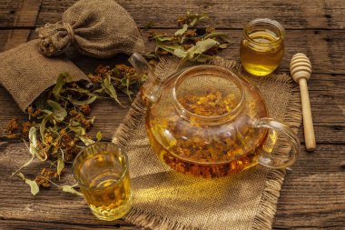 Linden çayı. Kuru kokulu çiçekler. Güneşli sabah kahvaltısı. Bağışıklık sistemini güçlendirmek için sıcak içecek, alternatif tıp. Klasik ahşap masa.