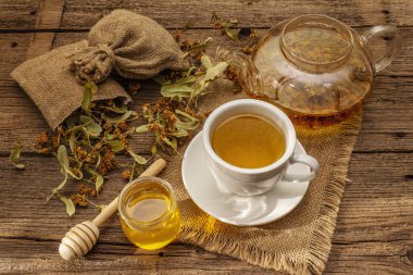 Linden çayı. Kuru kokulu çiçekler. Güneşli sabah kahvaltısı. Bağışıklık sistemini güçlendirmek için sıcak içecek, alternatif tıp. Klasik ahşap masa.