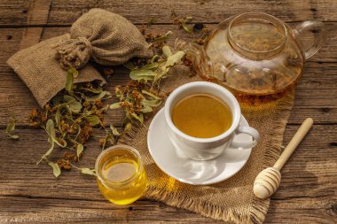 Linden çayı. Kuru kokulu çiçekler. Güneşli sabah kahvaltısı. Bağışıklık sistemini güçlendirmek için sıcak içecek, alternatif tıp. Klasik ahşap masa.