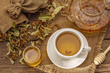 Linden çayı. Kuru kokulu çiçekler. Güneşli sabah kahvaltısı. Bağışıklık sistemini güçlendirmek için sıcak içecek, alternatif tıp. Klasik ahşap masa.