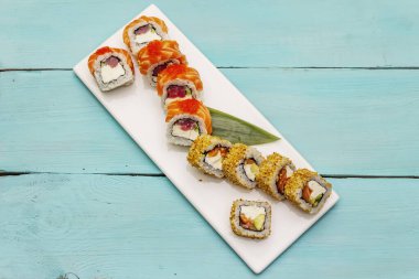 Çeşitli suşi setleri. Farklı taze malzemeli Japon ya da Kore dürümü. Moda turkuaz ahşap tahta arka plan