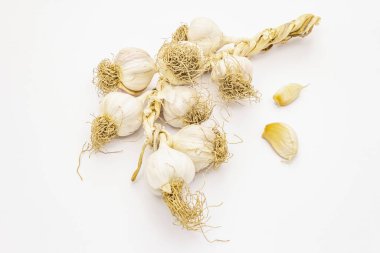 Beyaz arka planda izole edilmiş olgun sarımsak kafalar. Bir mahsülün depolanması için geleneksel demet