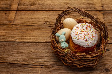 Paskalya pastası, tavşanlar ve hasır sepette yumurtalar. Geleneksel Ortodoks şenlik ekmeği, klasik ahşap tahta arka plan