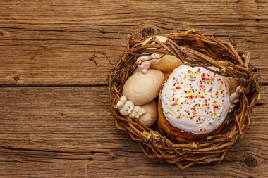 Paskalya pastası, tavşanlar ve hasır sepette yumurtalar. Geleneksel Ortodoks şenlik ekmeği, klasik ahşap tahta arka plan