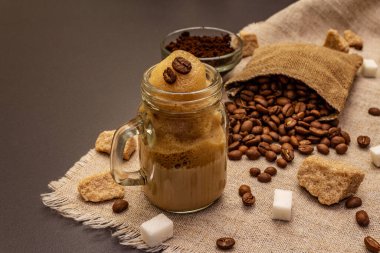 Duvarcı kavanozunda Dalgona kahvesi. Kore kremalı kahve içeceği. Siyah taş arka planda moda karantina içeceği, şeker ve kahve çekirdekleri