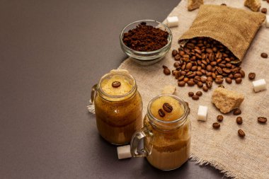 Duvarcı kavanozunda Dalgona kahvesi. Kore kremalı kahve içeceği. Siyah taş arka planda moda karantina içeceği, şeker ve kahve çekirdekleri