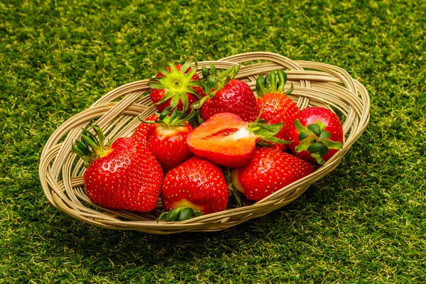 Sweet fresh strawberry in wicker basket. Ripe berries fruit, tasty ingredient for many dishes. Artificial green grass background