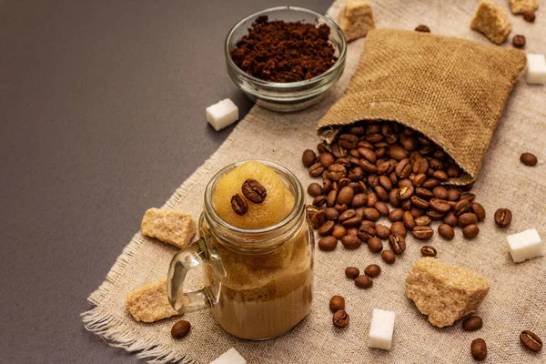 stock image Dalgona coffee in mason jar. Korean fluffy whipped coffee beverage. Trendy quarantine drink, sugar and coffee beans on black stone concrete background