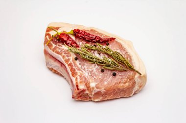 Beyaz arka planda çiğ domuz bifteği. Baharatlar, deniz tuzu, biberiye, acı biber.