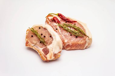 Beyaz arka planda çiğ domuz bifteği. Baharatlar, deniz tuzu, biberiye, acı biber.