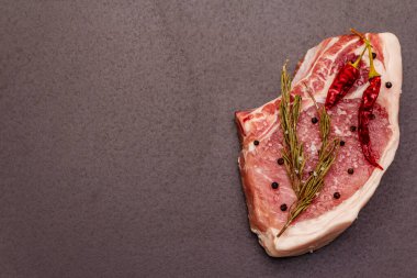 Moda siyah taş arka planda çiğ domuz eti. Baharatlar, deniz tuzu, biberiye, kırmızı biber, üst görünüm, kopyalama alanı