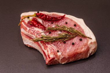 Moda siyah taş arka planda çiğ domuz eti. Baharatlar, deniz tuzu, biberiye, biber biberi, yakın çekim.