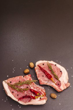 Moda siyah taş arka planda çiğ domuz bifteği. Baharatlar, deniz tuzu, biberiye, kırmızı biber, üst görünüm, kopyalama alanı