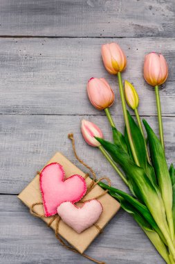 Tebrik kartı, duvar kağıdı, fon. Anneler Günün kutlu olsun, Sevgililer Günü ya da Düğün. Nazik pembe laleler, el yapımı keçeli kalp, sıfır atık paketleme hediyesi. Tahta kaplama arka plan