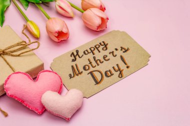 Anneler Günü için tebrik kartı. Nazik pembe laleler, el yapımı keçeli kalpler, pembe arka planda sıfır atık paketleme hediyesi.