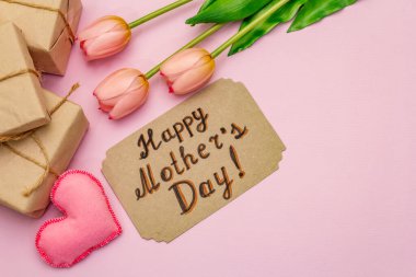 Anneler Günü için tebrik kartı. Nazik pembe laleler, el yapımı keçeli kalpler, pembe arka planda sıfır atık paketleme hediyesi.