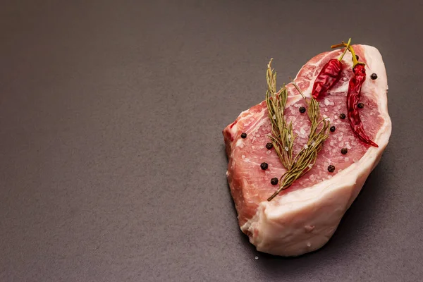 Rauwe Varkenssteak Trendy Zwarte Stenen Ondergrond Specerijen Zeezout Rozemarijn Chili — Stockfoto