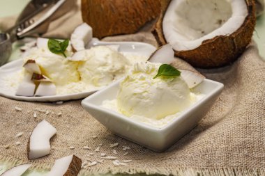 Laktozsuz hindistan cevizli dondurma. Özel kaşık, yarım meyve, gevrek. Vejetaryen tatlı konsepti. Açık yeşil arkaplan