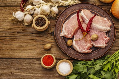 Çiğ domuz eti. Taze fileto, baharat, mis kokulu sebze ve maydanoz. Eski ahşap tahta masa, üst görünüm.