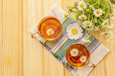 Papatya çayı. Taze çiçekler, yaz sıcak içecek konsepti. Alternatif tıp, yaşam tarzı. Tahta arka plan, üst görünüm.