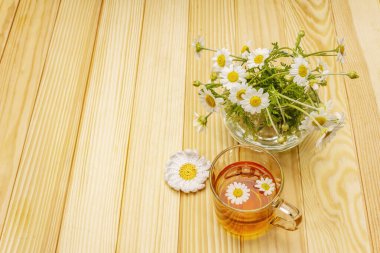 Papatya çayı. Taze çiçekler, yaz sıcak içecek konsepti. Alternatif tıp, yaşam tarzı. Tahta kaplama arka plan, kopyalama alanı.
