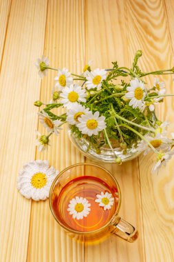 Papatya çayı. Taze çiçekler, yaz sıcak içecek konsepti. Alternatif tıp, yaşam tarzı. Tahta kaplama arka plan, kapat.