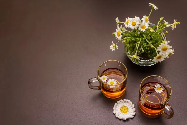 Chamomile tea. Fresh flowers, summer hot drink concept. Alternative medicine, lifestyle. Trendy black stone concrete background, top view