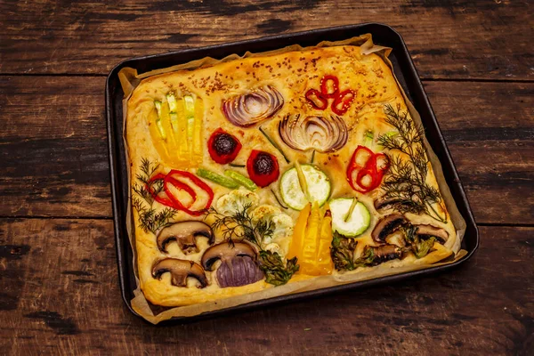 Renkli bahçe Focaccia 'sı. Taze sebzeler, zeytinyağı, yeşiller. Geleneksel İtalyan pastanesi. Eski tahta arka plan