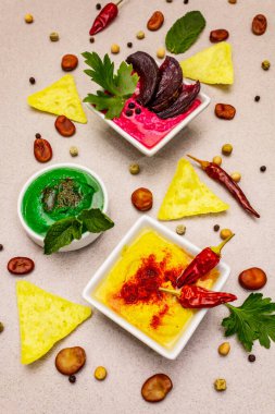 Humus, sağlıklı vejetaryen yemeği. Üç çeşit: klasik, nane ve pancar. Kuru fasulye, bir parça pide, baharatlar. Taş beton arka plan