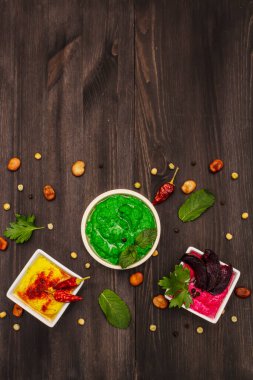 Humus, sağlıklı vejetaryen yemeği. Üç çeşit: klasik, nane ve pancar. Kuru fasulye, baharat, taze yapraklar. Moda siyah tahta kaplama arka planı