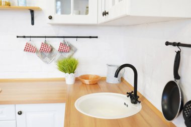 İskandinav tarzı beyaz mutfağı, mutfak detaylarını, ahşap masa üzerindeki ağaç bitkisini, beyaz seramik tuğla duvar zeminini görüntüle