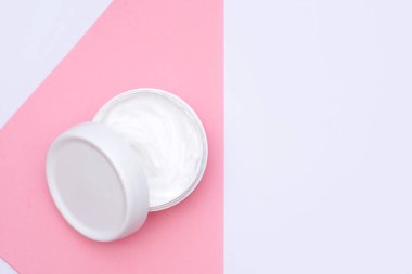 Pastel pembe ve beyaz arkaplandaki kadınlar için beyaz doğal bitkisel krem kavanozu..