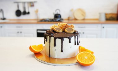 Çikolatalı elmalar ve wafflelarla süslenmiş doğum günü pastası. Mutfaktaki beyaz masada, portakalların yanında.