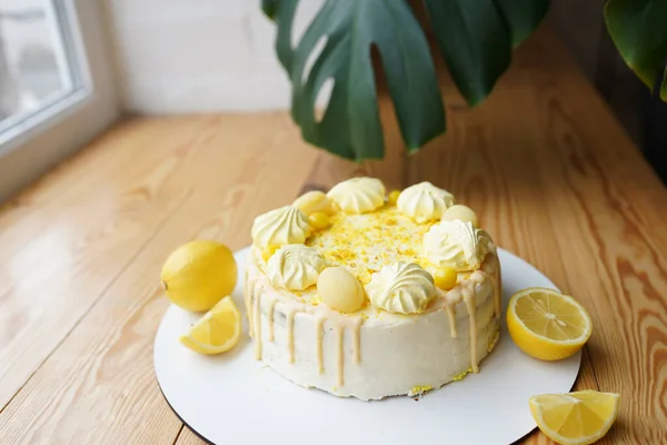 Tender lemon cake with candid lemon and meringue on wooden table