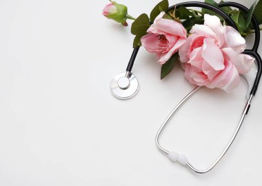Beyaz arka planda steteskop ve pembe güller. Kopyalama alanı olan üst görünüm. Ulusal Doktor Günü. Mutlu hemşire günleri..