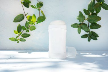 Koltuk altları için yeşil dalları ve gölgeleri olan mavi deodorant.