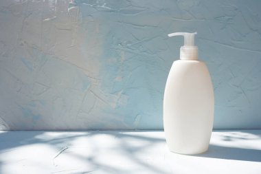 Vücut kremi losyonu şişesi. Lüks ambalaj tüpü. Beton mavi arka plan, aroma spa kokusu.