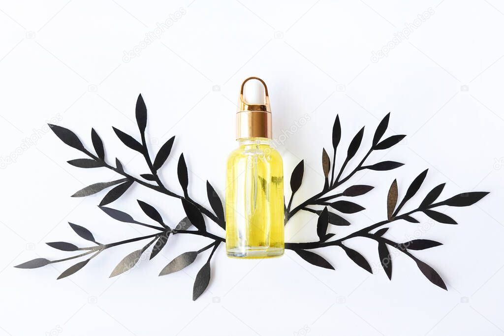 Yellow bottle of perfume with greenery on white background