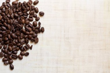 Koyu kahve taneleri açık ahşap masanın üzerinde duruyor, arka plan görüntüsü. metin için yer